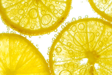 Fresh lemon slice in water with bubbles on white background