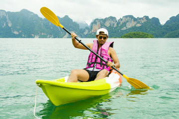 Young Asia man paddling in Chiewlarn dam in Surat Thani, Thailand