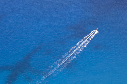 Aerial image of motorboat floating in a turquoise blue sea water. 