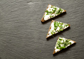 Fast canapes with soft cheese, parsley and dill on a dark backgr