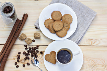 Ginger biscuits, cinnamon, a cup of hot coffee. Walnuts, hazelnuts on a wooden background