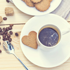 Ginger biscuits, cinnamon, a cup of hot coffee. Walnuts, hazelnuts on a wooden background. Tonned photo.