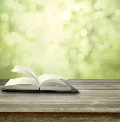 Open book on table and spring green background