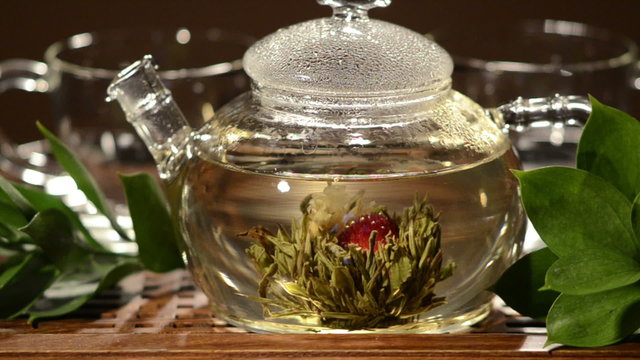 horizontal  photo  of the glass teapot with green tea in cup, on  on brown backgrpund, closeup