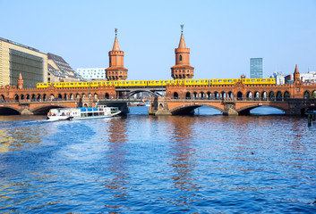 Oberbaumbrücke (Oberbaum Bridge) with subway and boat on the river Spree, Berlin - obrazy, fototapety, plakaty
