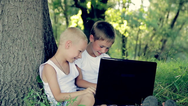 children close up in the park playing on the computer