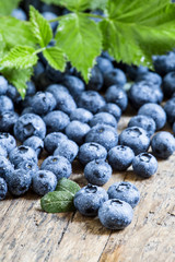 Fresh blueberries and green leaves on the old wooden background,