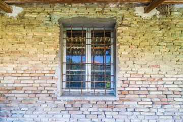 Fototapeta na wymiar iton bars window in dilapidated brick wall
