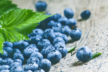 Fresh blueberries and green leaves on the old wooden background,