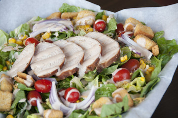 salad with sliced turkey on top with lots of vegetables 