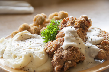 Chicken fried steak with mashed potatoes and country gravy with fried okra.