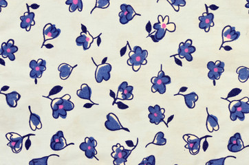 Floral pattern on blue fabric. Small blue flowers and hearts print as background.