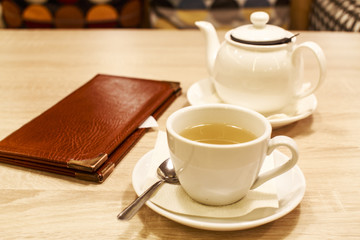restaurant bill. folder with the score at restaurant table with a teapot and a cup of tea