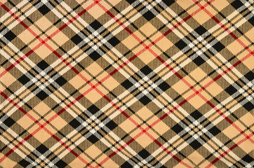 Scottish tartan pattern. Orange with red, white, black plaid print as background. Symmetric rhombus square pattern.