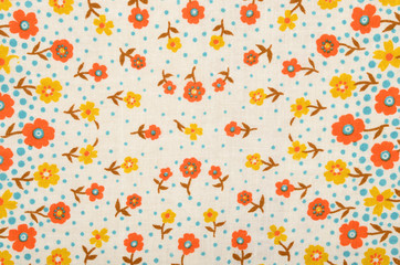Small floral pattern on fabric. Yellow and orange flowers with blue dots print as background. - 89137701