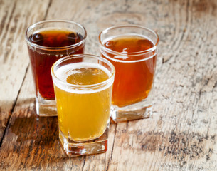 Three kinds of beer on old wooden background, selective focus