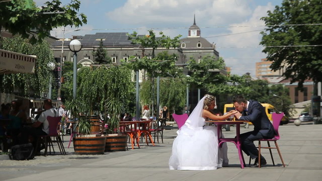 bride and groom sitting in cafe at the street