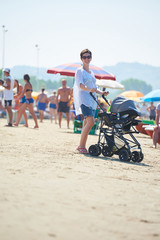 mother walking on beach and push baby carriage