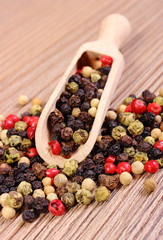 Fresh colored pepper with spoon on wooden background