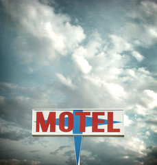 aged and worn vintage motel sign with dramatic sky
