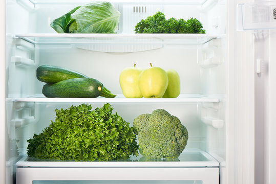 Open refrigerator full of green fruits and vegetables. Weight loss diet concept.