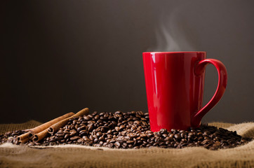 Red Coffee cup and coffee beans around on wooden table