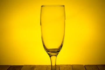 empty wineglass on yellow backlight background, closed up