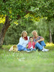 Family with apples and book in park