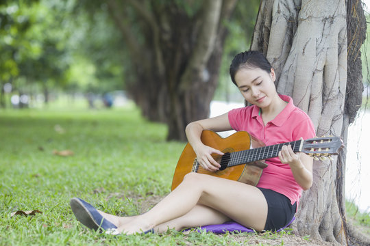 Young attractive woman playing acoustic guitar