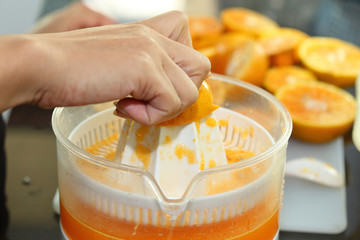 orange fruit squeezed with woman hand in juicer machine, orange