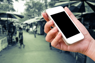 woman hand holding the phone tablet on blur market background
