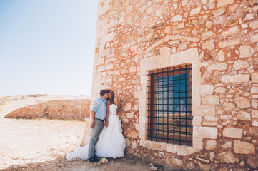 couple in love, bride and groom standing near the stone wall