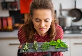 Woman with eyes closed smelling fresh herbs