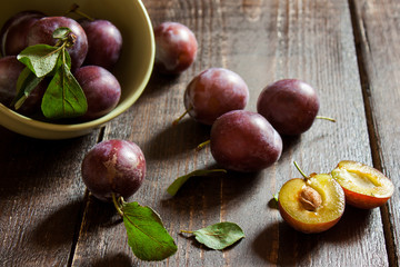 спелые сливы в тарелке на деревянном столе