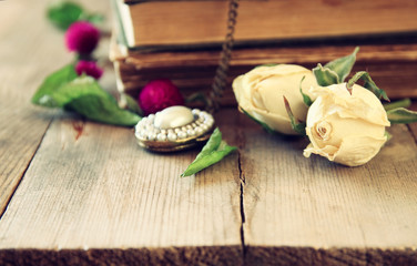 selective focus image of dry rose, antique necklace and old vintage books