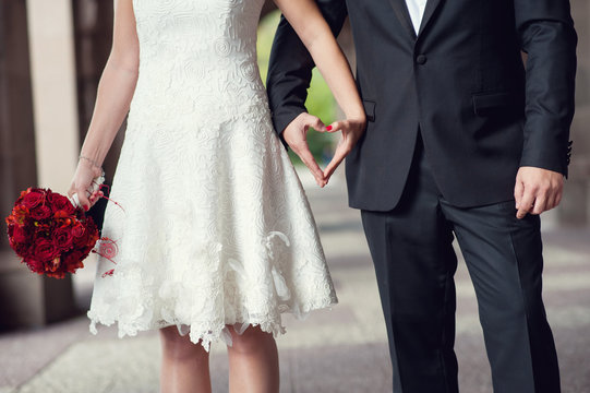 Newlyweds, hands heart and wedding bouquet