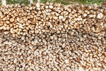 Ready firewood. Various kinds of wooden logs stacked on top of each other. Stack of wood, firewood, background. Dry chopped firewood logs ready for winter.

