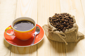 coffee cup and roast coffee in sack on wood table