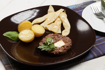 Grilled hamburger with potatoes and yellow beans.