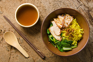 Yellow noodles served with sliced pork
