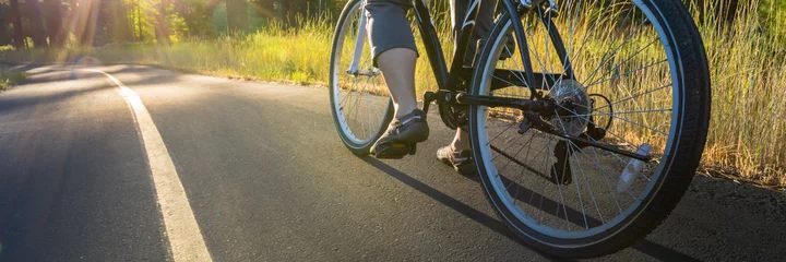 Poster Vélo Faites du vélo sur le chemin asphalté illuminé par le soleil.
