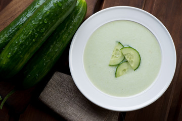 Above view of cucumber cream-soup in a glass plate, close-up