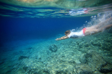 Fototapeta na wymiar underwater view of young girl taking a header into crystal clear open ocean water