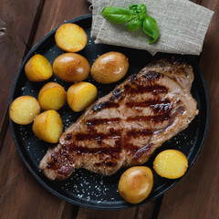 Close-up of grilled striploin steak with potatoes in a pan