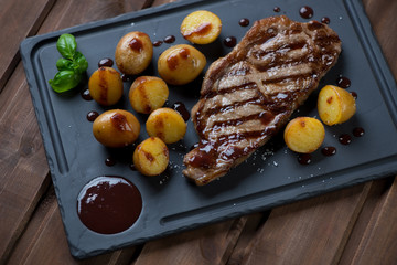 Basalt dish with grilled striploin beefsteak, potatoes and sauce