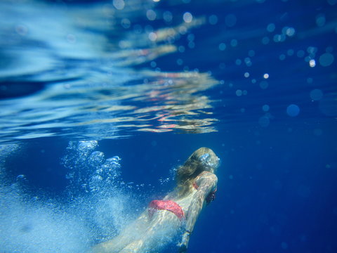 underwater view of young girl diving in crystal clear open waters