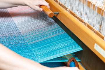 Hands of a woman who weaves on a loom