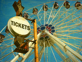 aged and worn vintage photo of ferris wheel and ticket sign