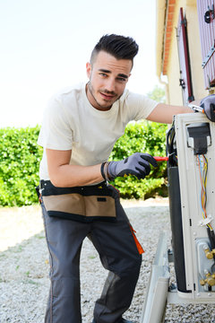 handsome young man electrician installing air conditioning in a client house