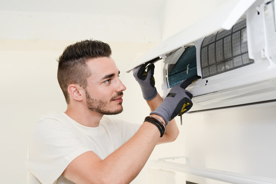 handsome young man electrician installing air conditioning in a client house